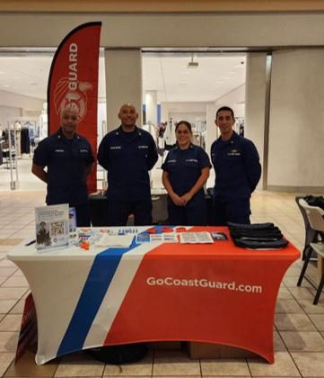 Four people posing at a recruiting table